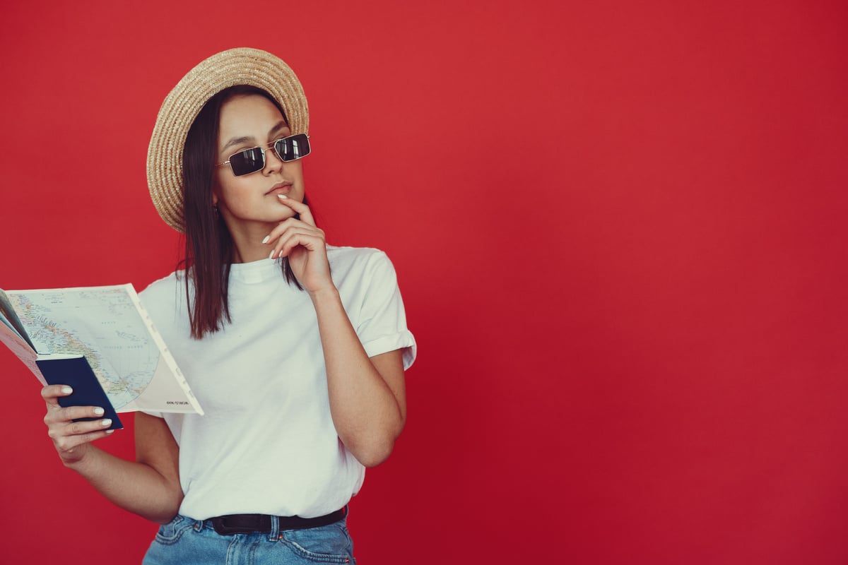 Pensive young female hipster with map on red background